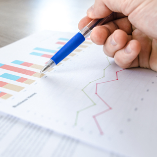 A person holding a pen against a graph on a sheet of paper