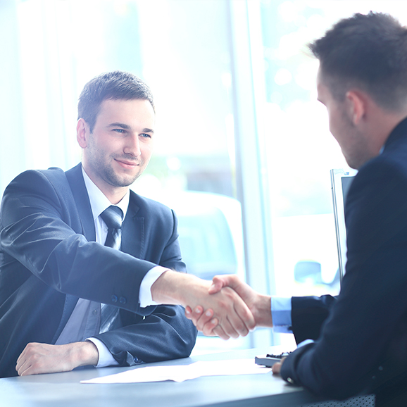 Two tax insurance business men are shaking hands over a table