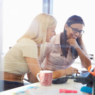 Two tax insurance business women are smiling looking at a laptop