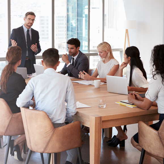 A group of tax insurance business men and women partaking in a tax risk management meeting around a large table