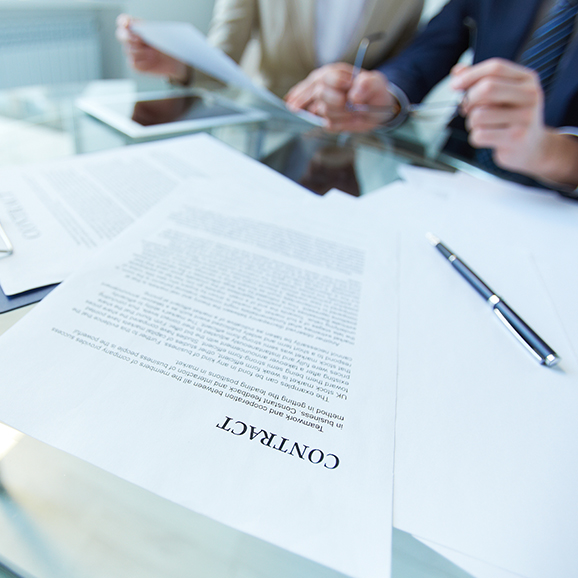 Two people working at a desk with papers titled 'Contract'